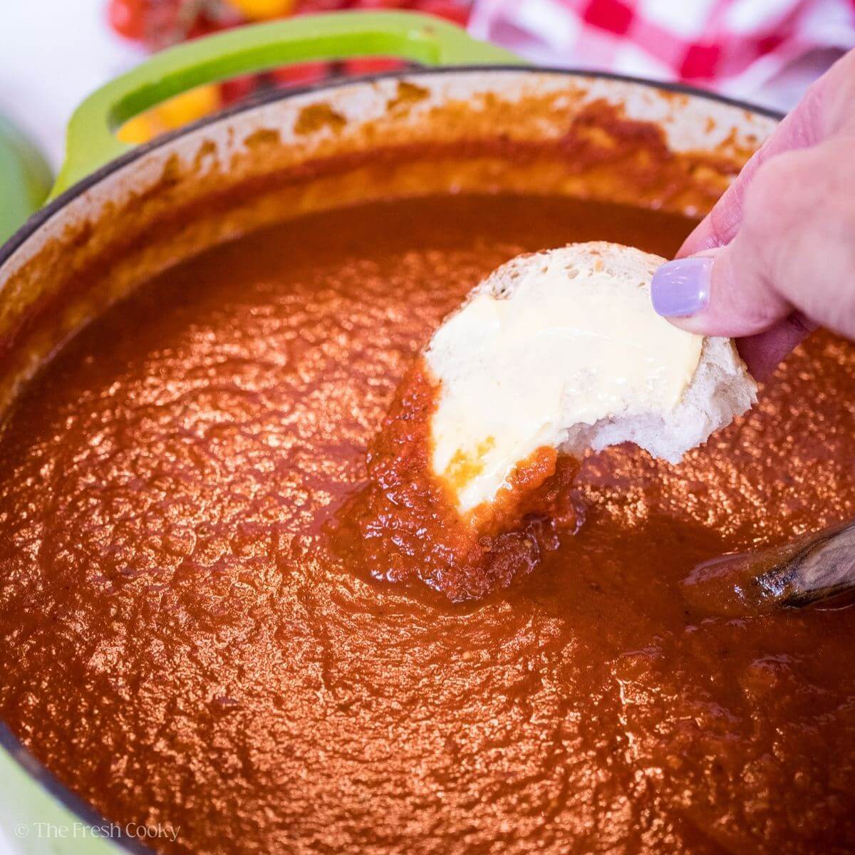 Dipping a piece of Italian bread into red sauce.