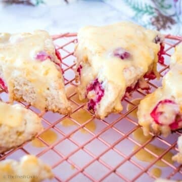 Cranberry Oranges scones with orange glaze on a cooling rack.