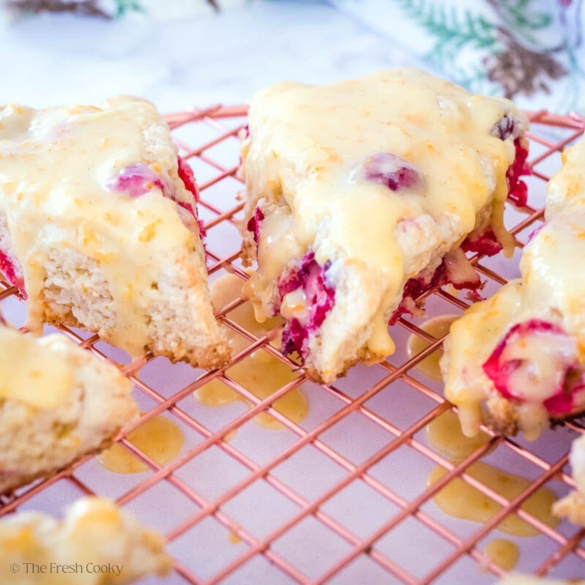 Cranberry Oranges scones with orange glaze on a cooling rack.
