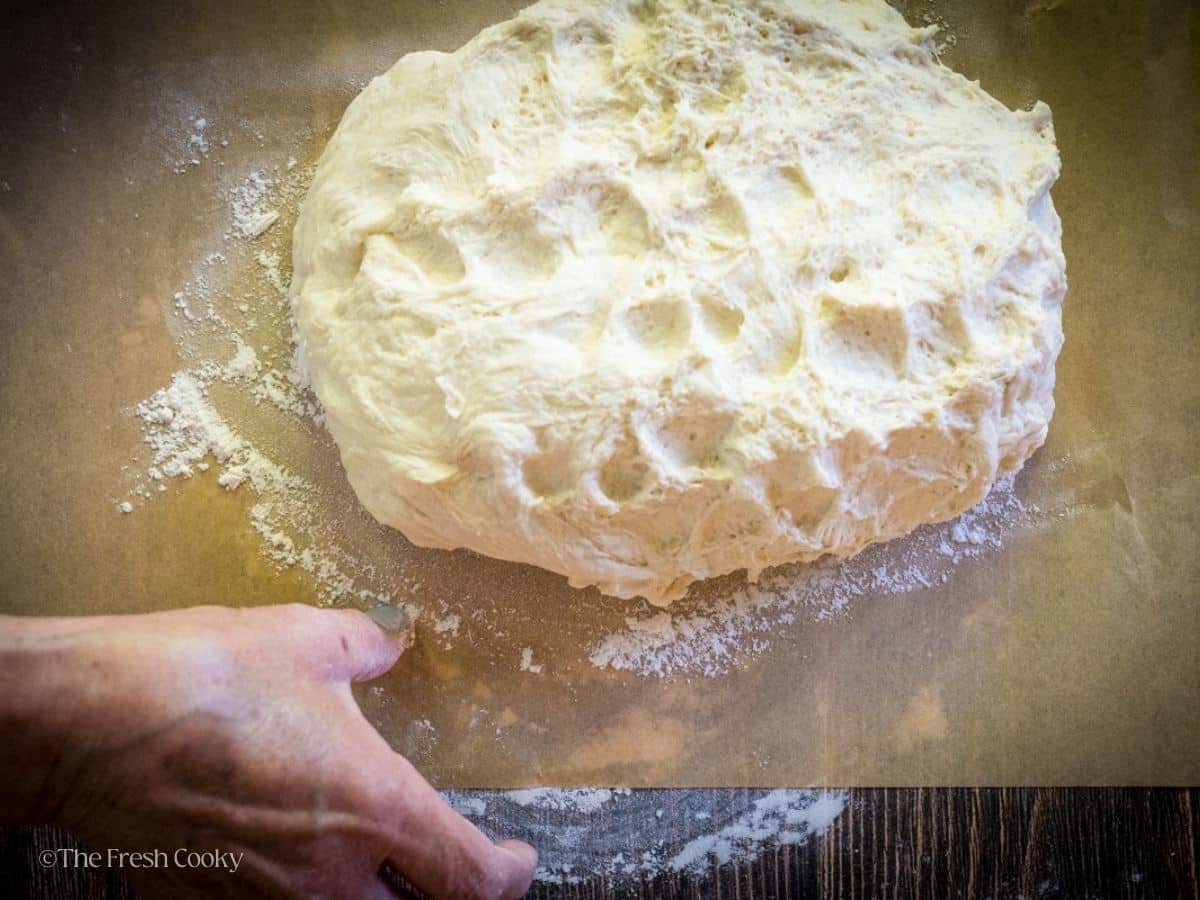 Bowl of sourdough inverted onto parchment paper.