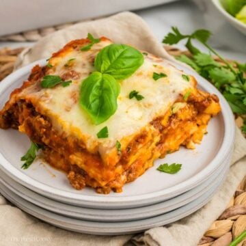 Slice of lasagna garnished with fresh basil and parsley.