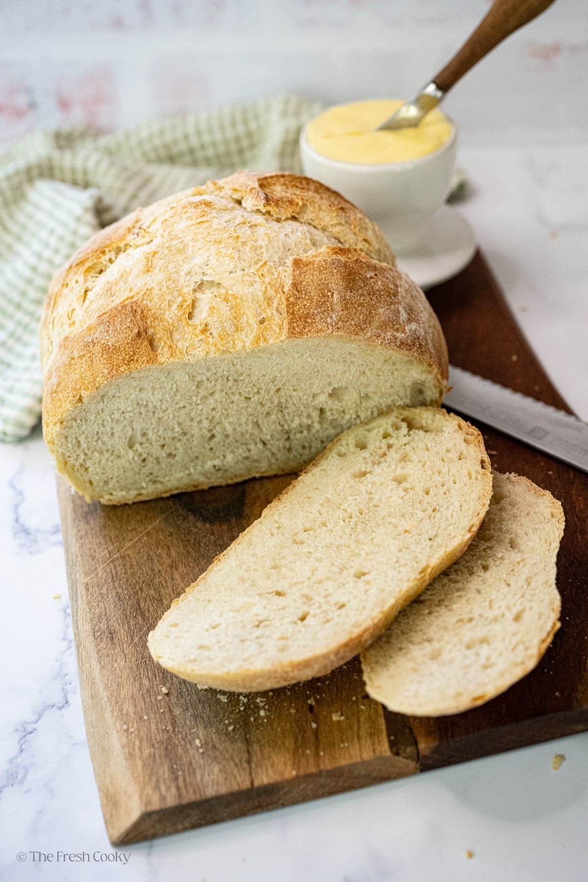 Sourdough bread loaf with some slices off the end on a wooden board.