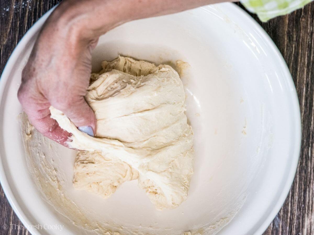 Folding the sourdough bread dough in a mixing bowl.