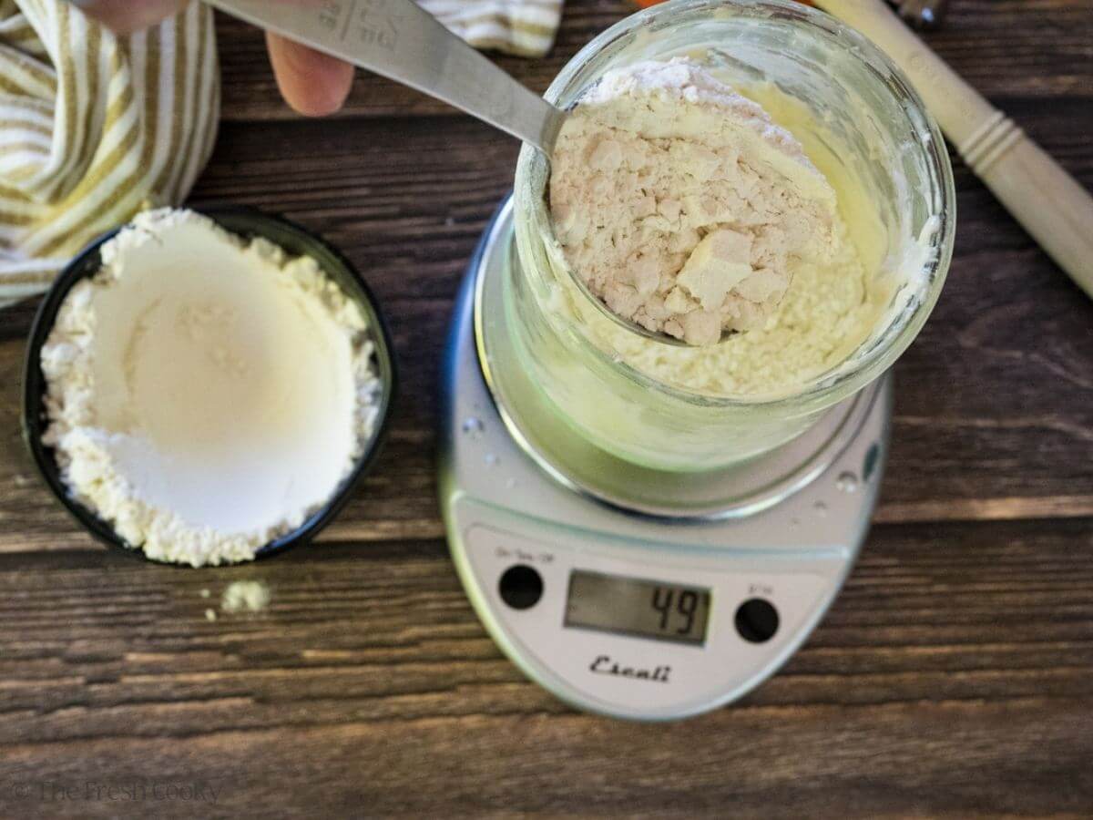 Adding flour to a sourdough starter on a scale.