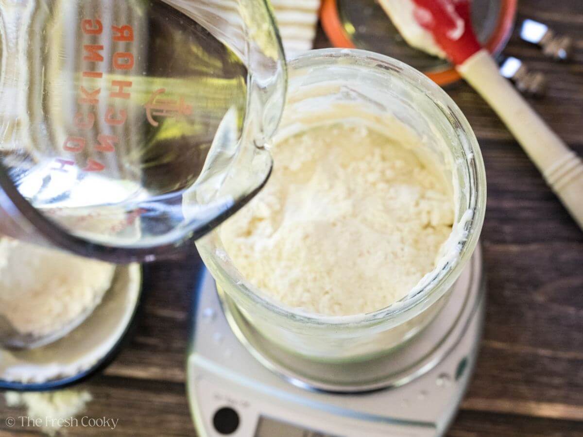 Adding water to the sourdough starter and fresh flour.