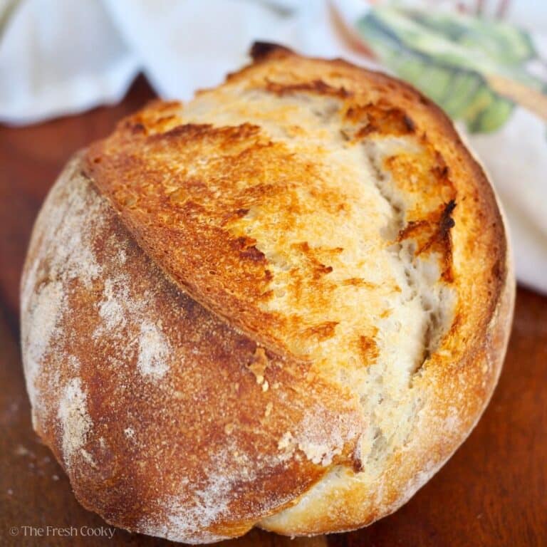 A crispy, golden crusted loaf of sourdough bread on a bread board.