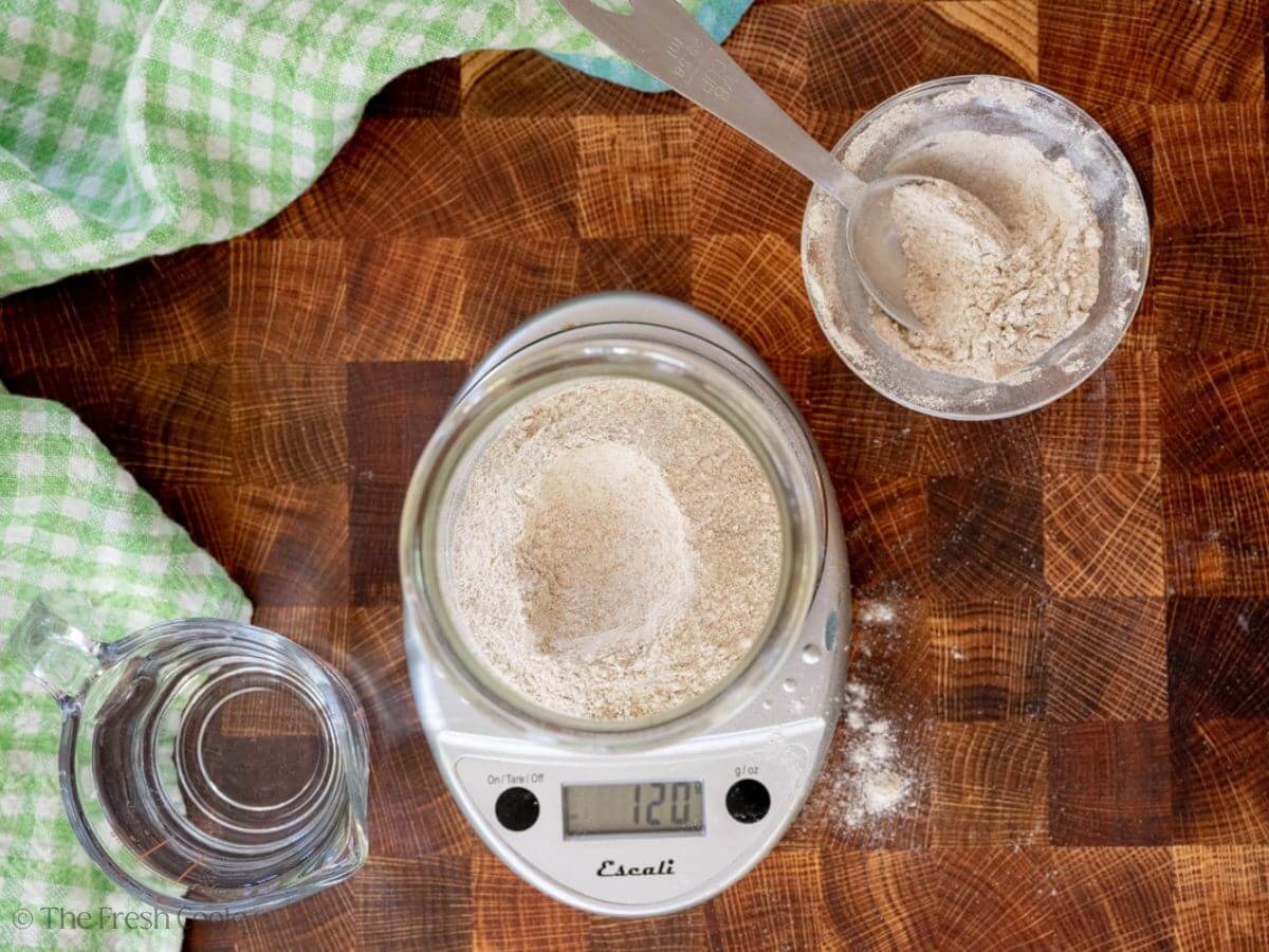 Flour placed in a glass jar on a kitchen scale.