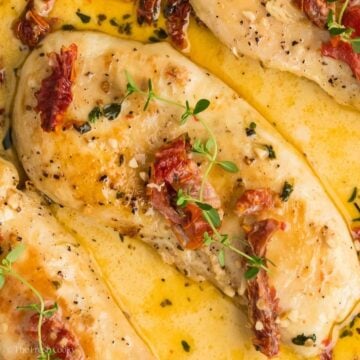 Close up shot of marry me chicken with sun-dried tomatoes and fresh thyme on top.