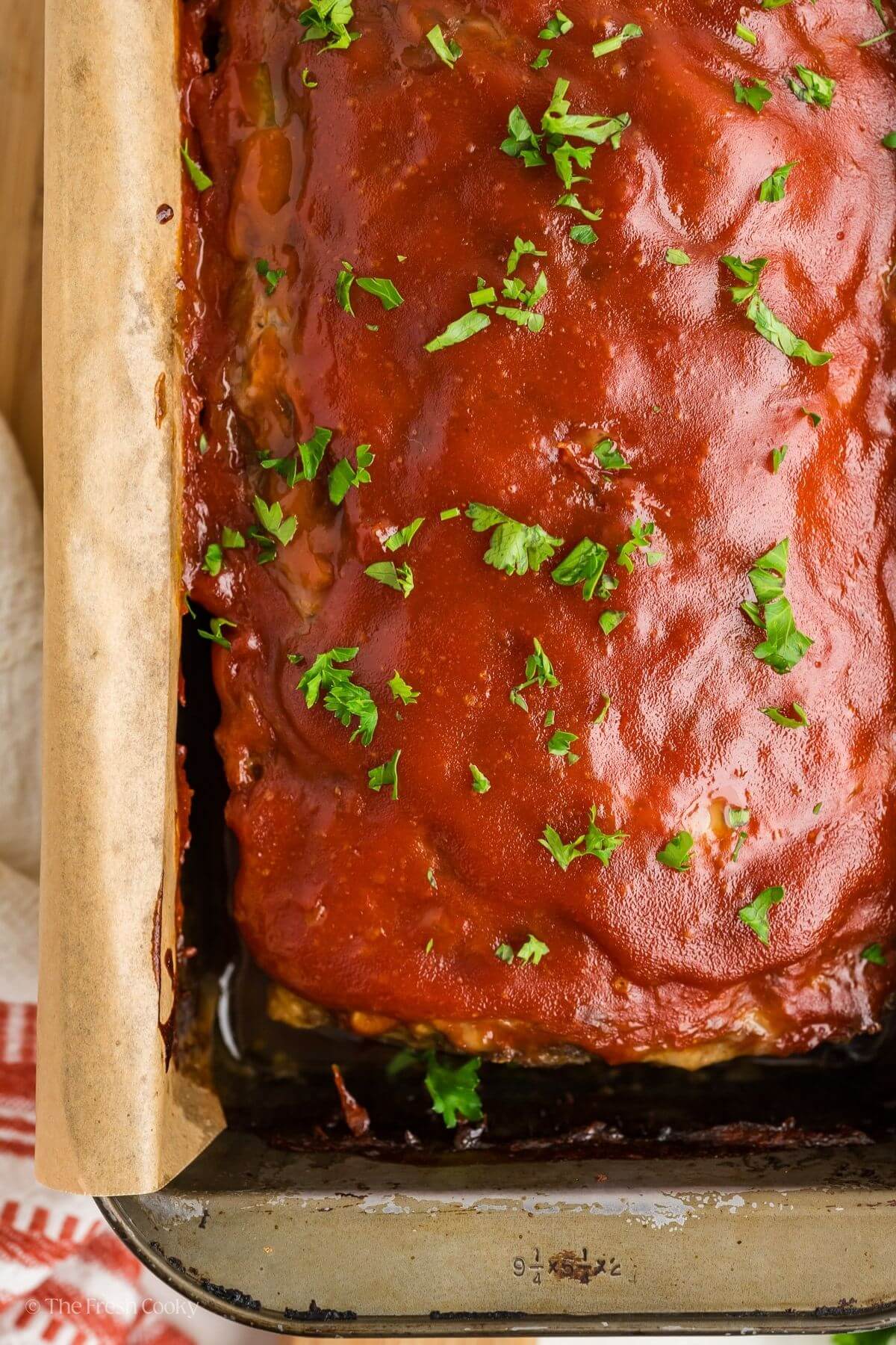 Overhead shot of cooked meatloaf with glaze and fresh parsley on top.