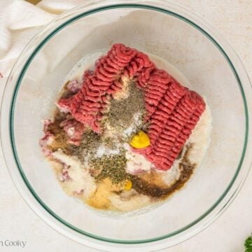 Meatloaf ingredients in a glass mixing bowl before being mixed together.