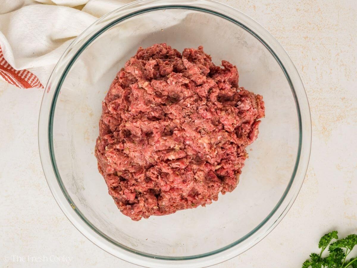 Meatloaf ingredients mixed together in a glass mixing bowl.