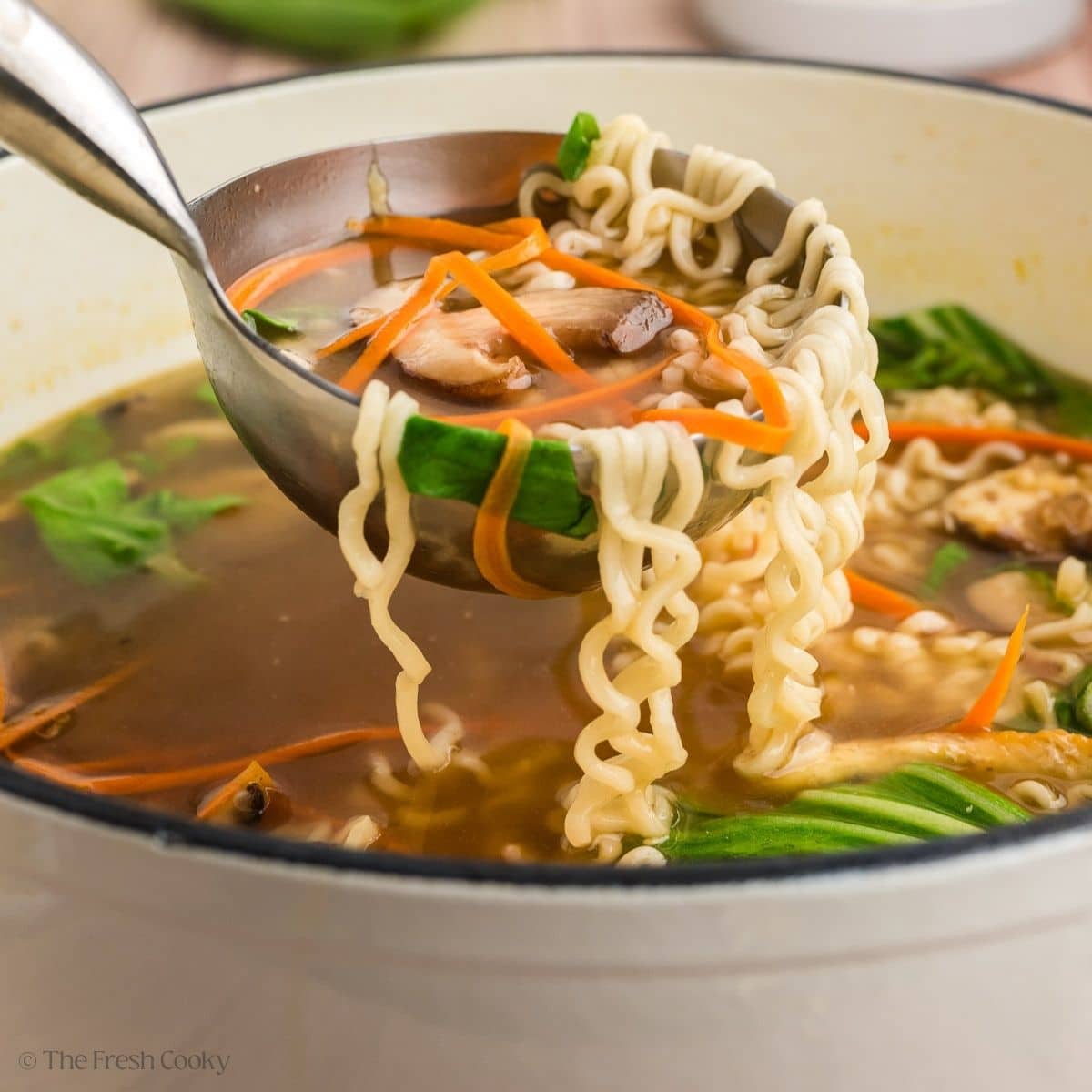 Ladeling a serving of ramen noodles with springy noodles, vegetables and more.