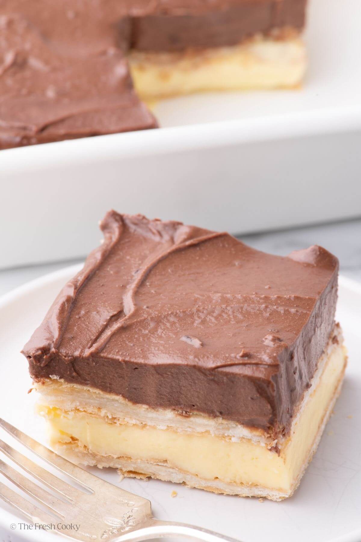 Slice of chocolate eclair cake with layers of custard and ganache with puff pastry.