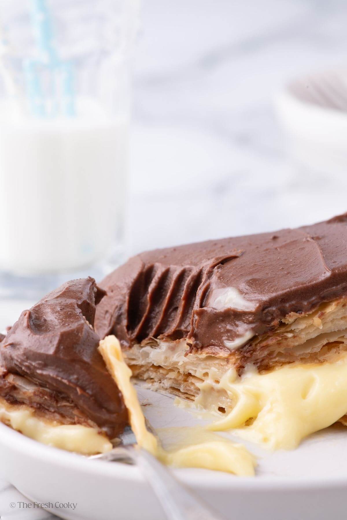 Fork taking a bite off of a slice of chocolate eclair cake on a plate.