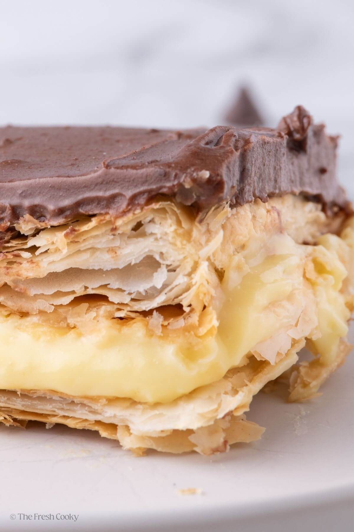 Close up view of the side of a slice of chocolate eclair cake on a plate.