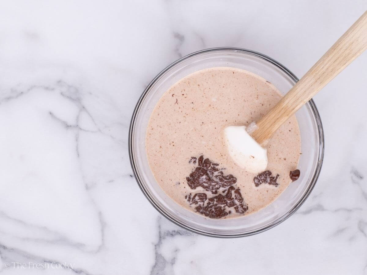Warm cream mixed with chocolate chips in a mixing bowl.