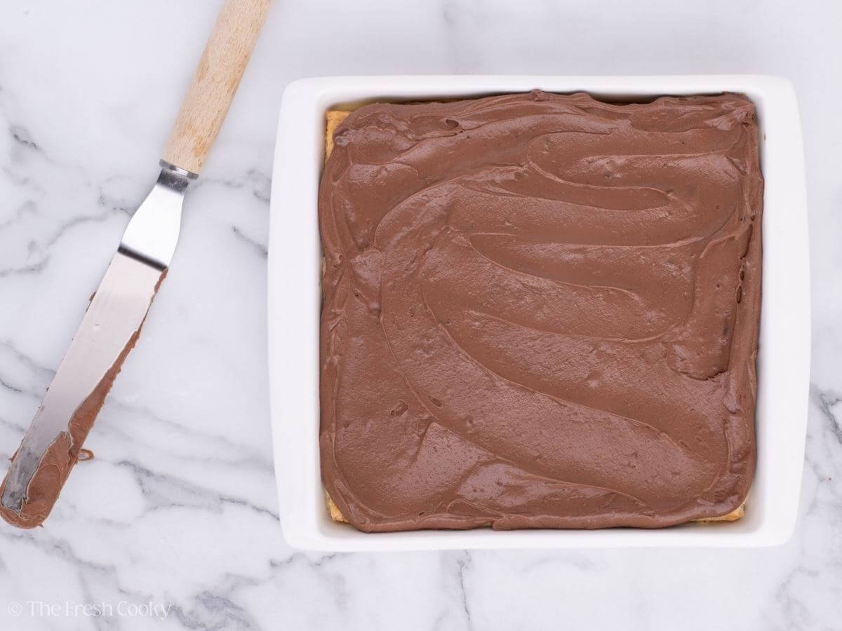 Layer of chocolate ganache on top of the chocolate eclair cake.