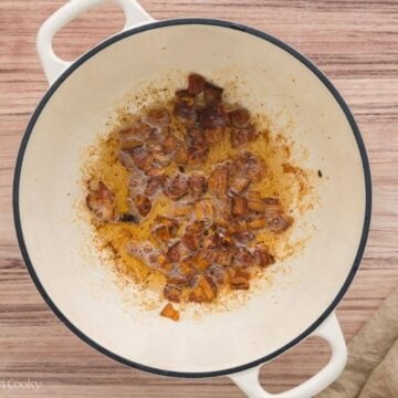 Pieces of bacon sizzling in the bottom of a large stock pot.