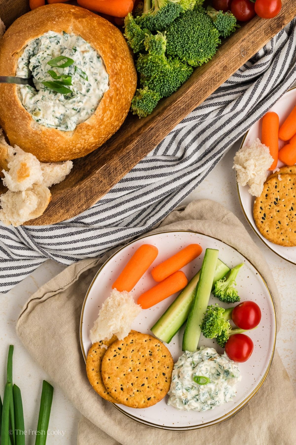 Spinach dip served ona plate with crackers and veggies. 