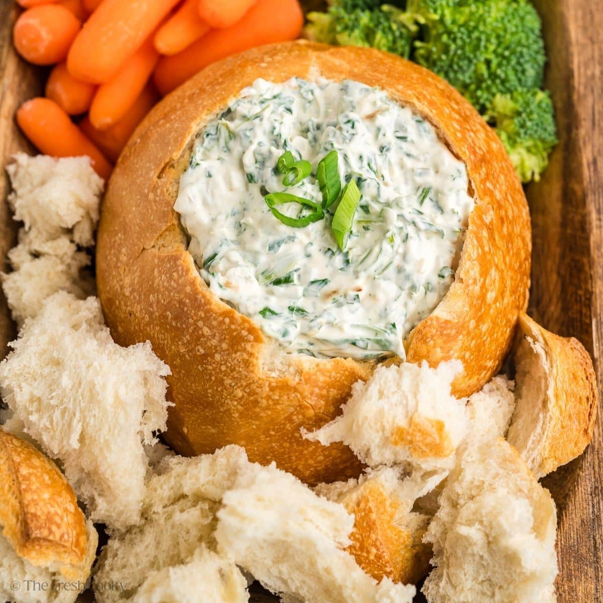 Vegetable dip in hollowed out bread bowl with veggies and bread for dipping. 