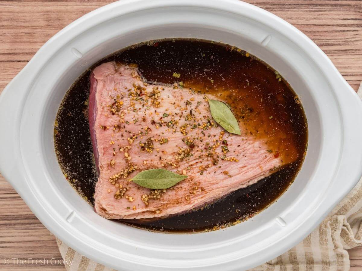 Beef broth mixture poured over the top of the corned beef brisket in a crock pot.