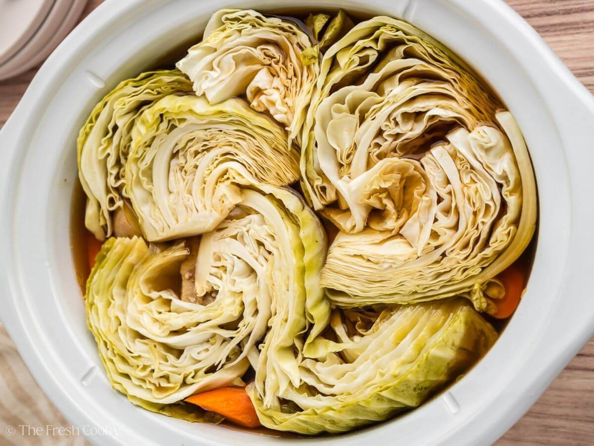 Cabbage tucked over the top of the beef in a crock pot.