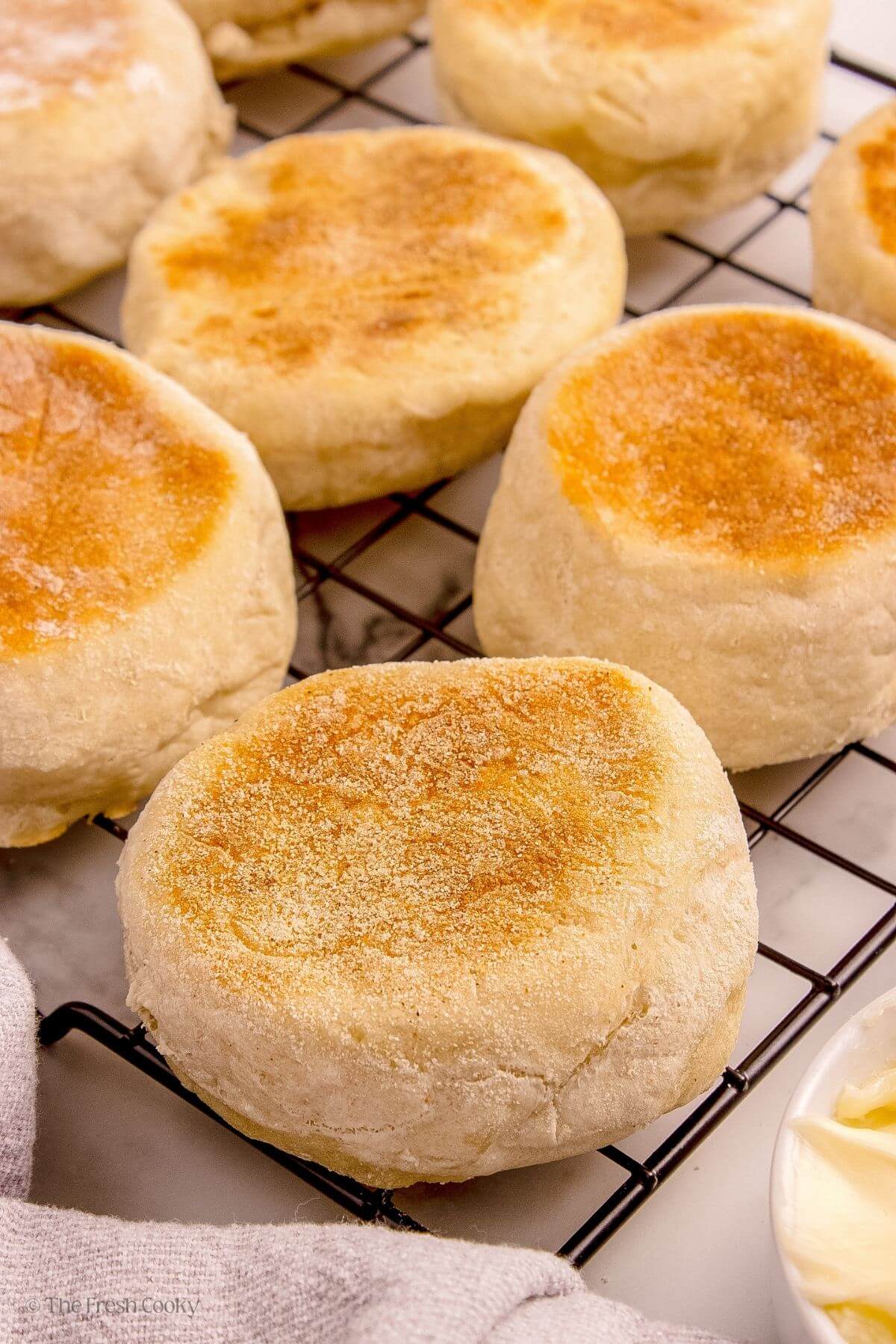 Cooked English muffins on a wire rack.
