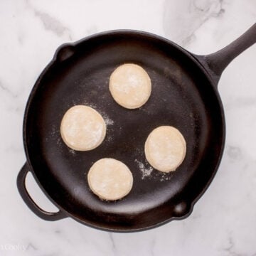 Four English muffins in a skillet.