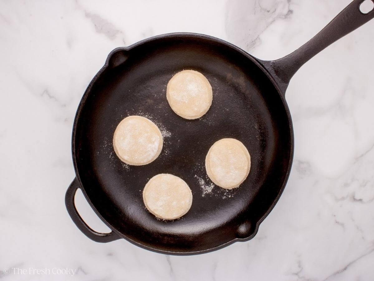 Four English muffins in a skillet.