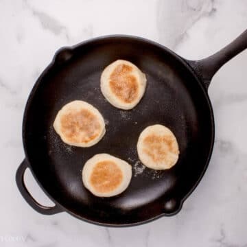 English muffins in a skillet after being flipped.
