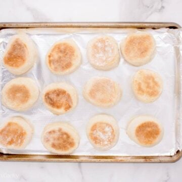 Seared English muffins on a sheet pan.