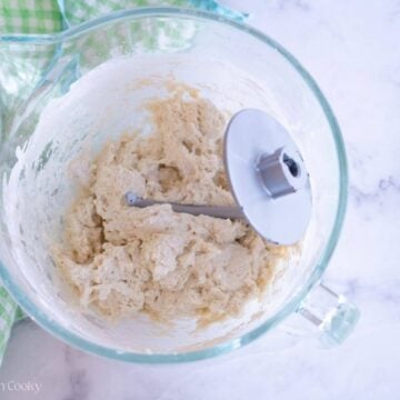English muffin dough in a stand mixer with a dough hook.