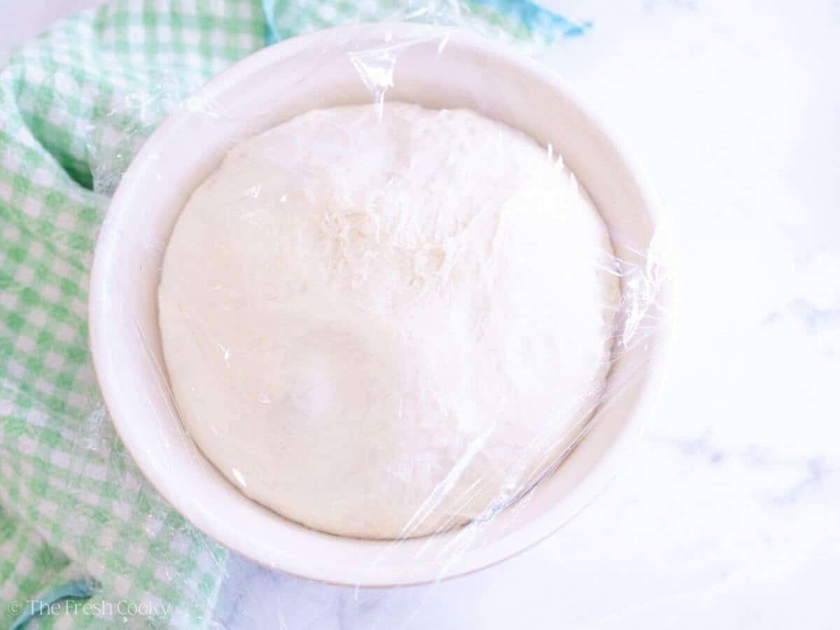 English muffin dough in a mixing bowl after rising.