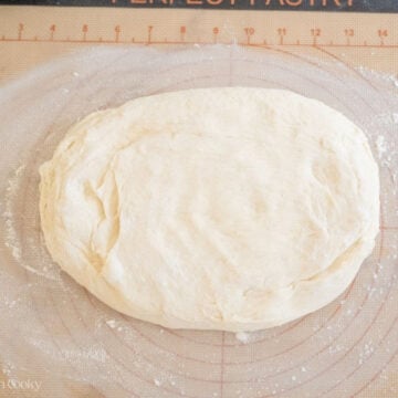 English muffin dough rolled out on a floured surface.