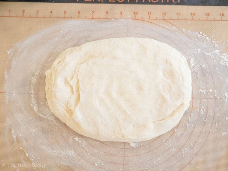 English muffin dough rolled out on a floured surface.