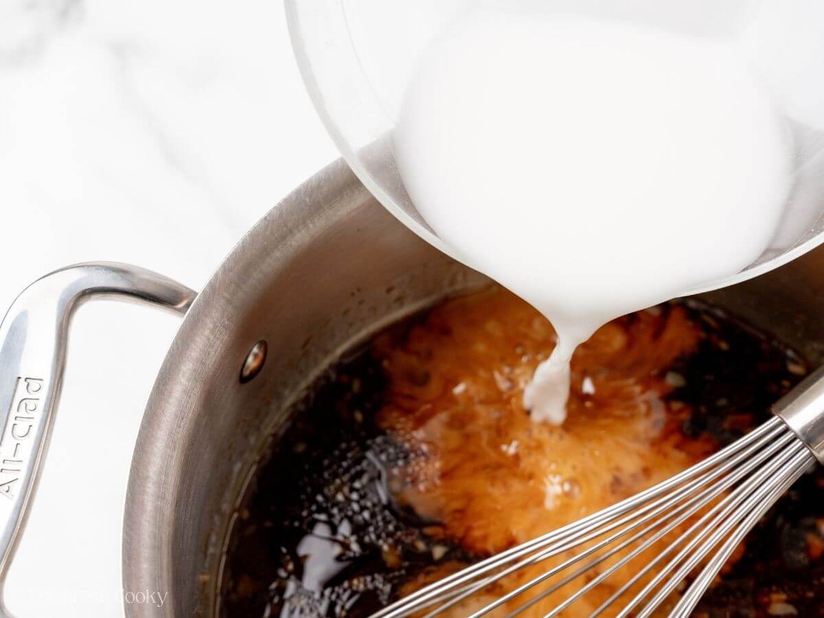Pouring cornstarch slurry into sauce. 