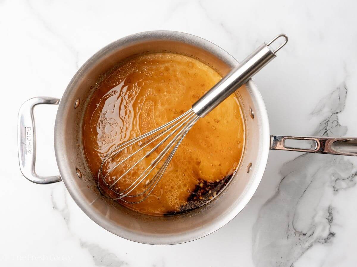 Whisking cornstarch slurry into saucepan.
