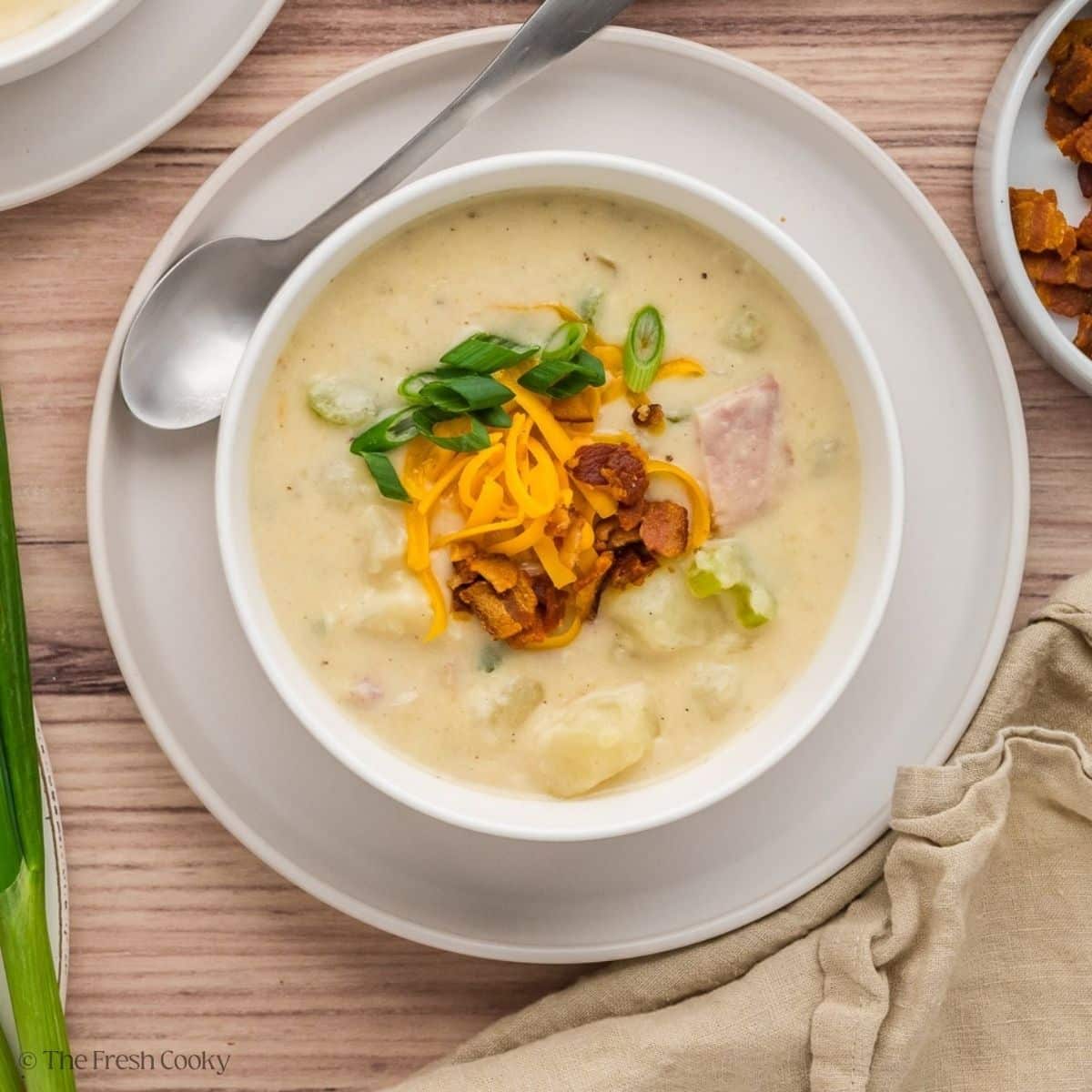 A bowl full of ham and potato soup with a spoon. 