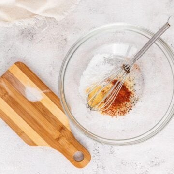 Spices in a glass mixing bowl with a whisk.