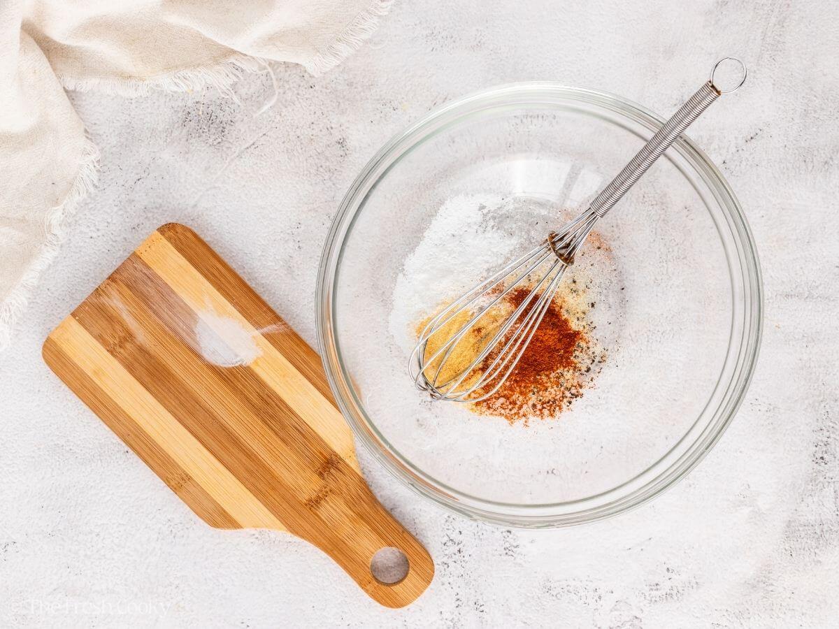 Spices in a glass mixing bowl with a whisk.