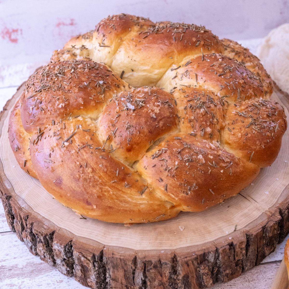 Beautiful round, braided Challah bread with salt and rosemary on top.