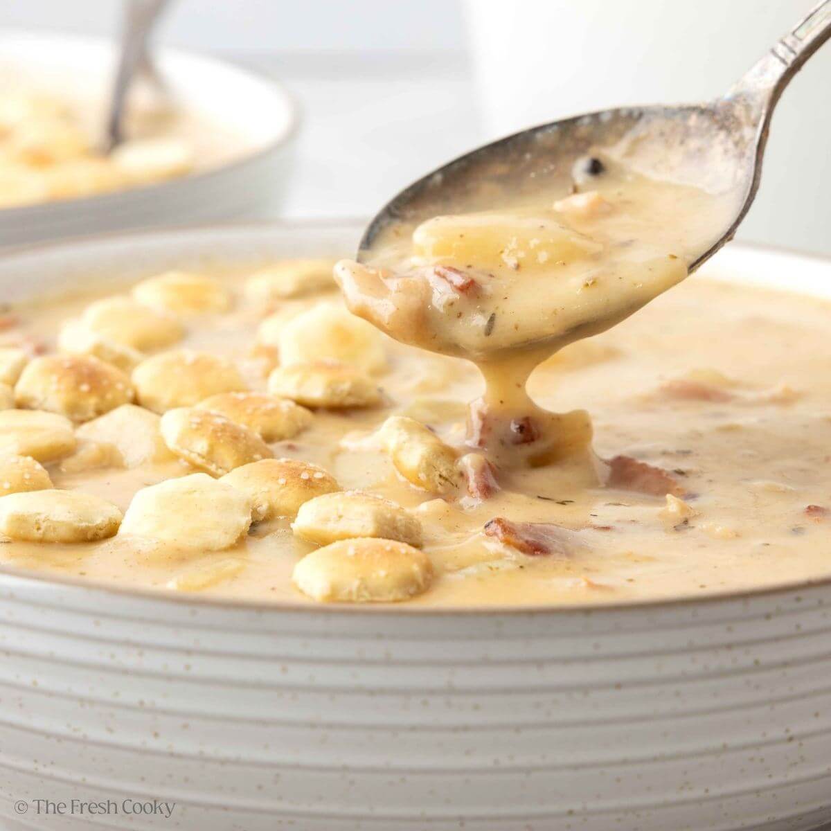 Spoon hovering over the bowl of clam chowder in a bowl to pick up a bite.