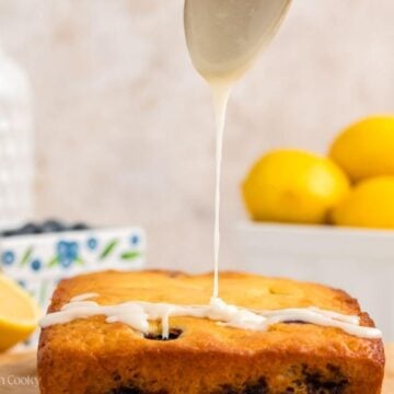 Spoon drizzling lemon glaze on top of the lemon blueberry bread.