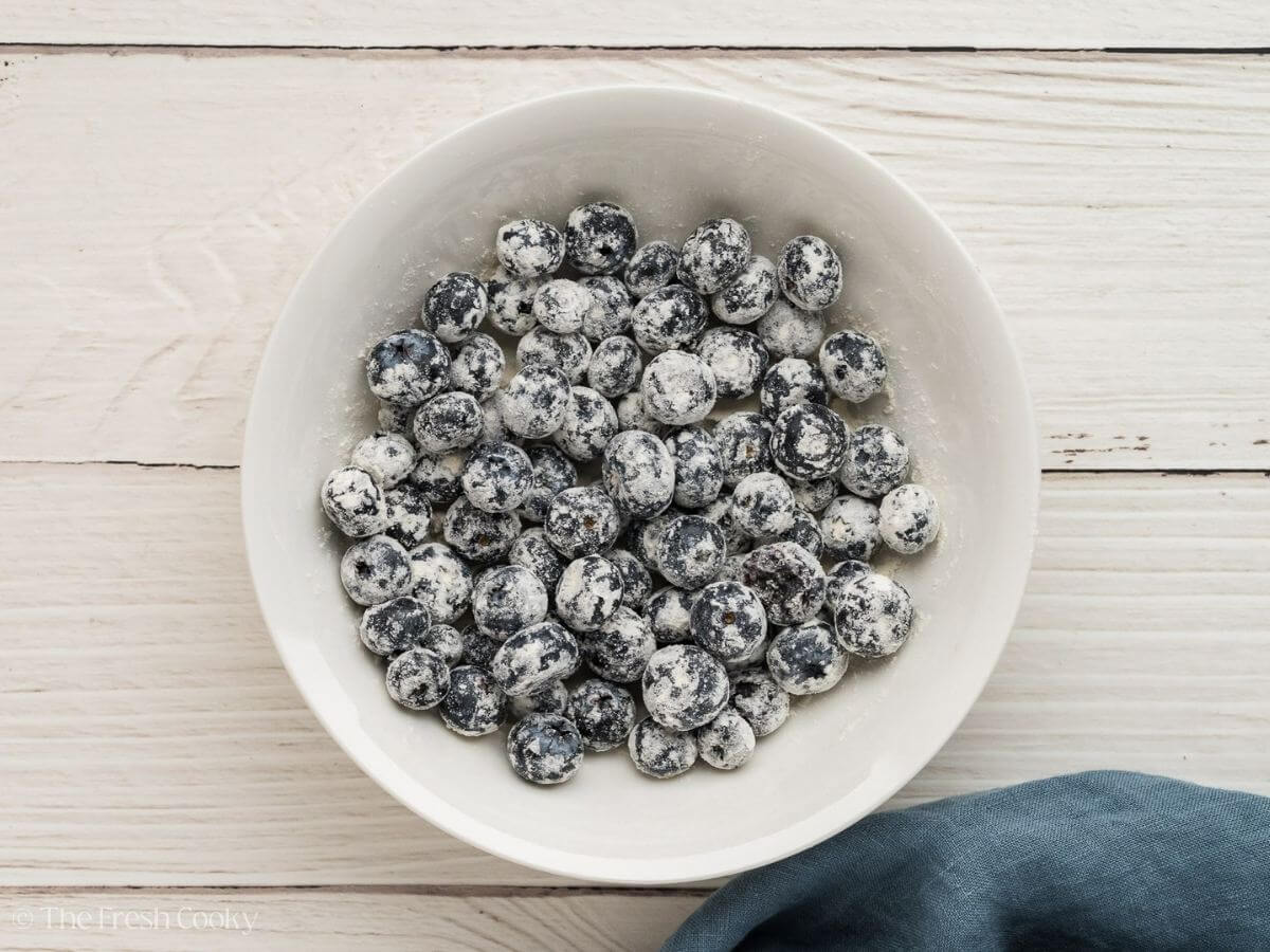 Fresh blueberries coated in flour in a bowl.