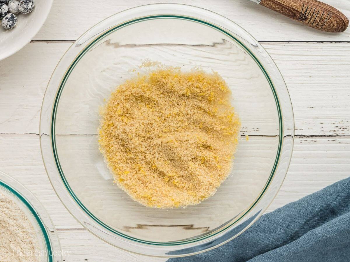 Lemon zest and sugar in a glass mixing bowl.