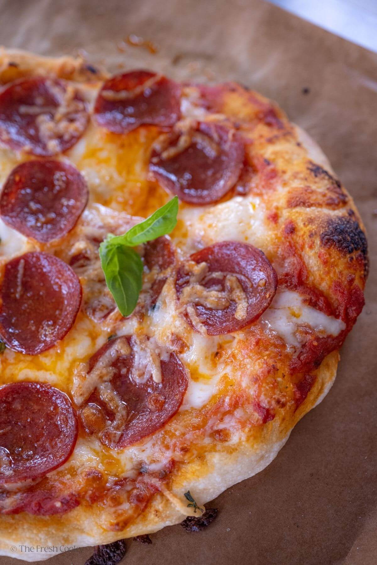 View of half of a pepperoni pizza on a piece of parchment paper.