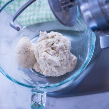 Sourdough pizza dough in a stand mixer bowl with the hook attachment.