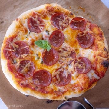 Pepperoni pizza on a piece of parchment paper after being baked.
