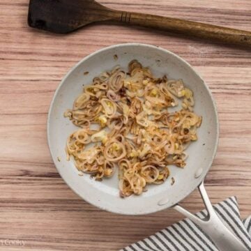 Sautéed sliced shallots in a skillet.
