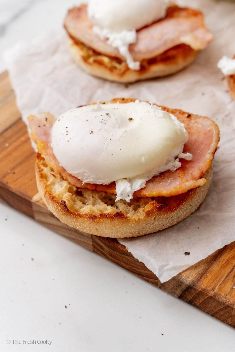 Assembling the eggs benedict by adding the poached egg on top.